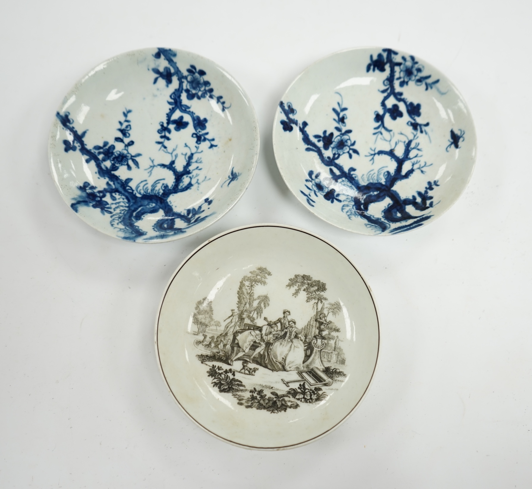 An 18th century Worcester saucer printed by Hancock and a pair of 18th century Liverpool prunus root saucers, Hancock saucer 12cm diameter. Condition - fair to good